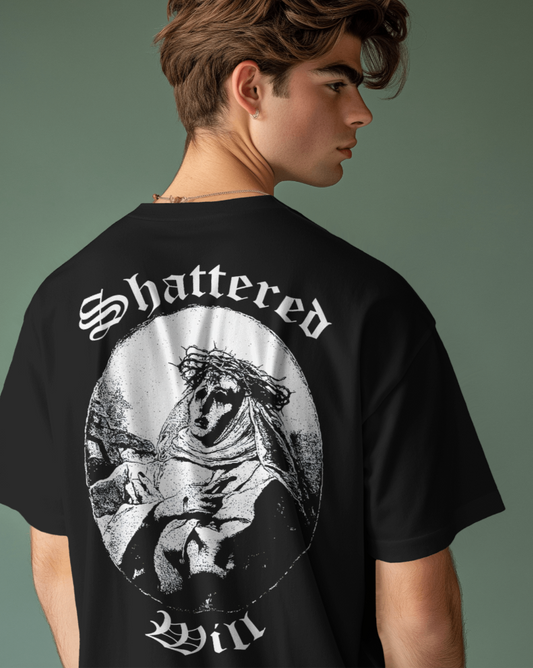 Person wearing a black t-shirt with 'Shattered Will' design on the back against a plain background